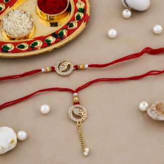 Bhaiya-Bhabhi Rakhi Set with paisley design, red thread, and pearl accents, alongside a decorated thali with kumkum and rice.