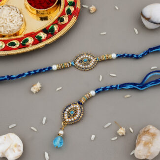 Elegant Evil Eye Bhaiya-Bhabhi Rakhi set with blue thread, designer gold detailing, pearl beads, and a hanging blue crystal charm, displayed with kumkum-chawal thali.