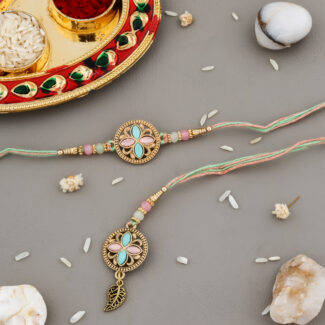 Bhaiya-Bhabhi Rakhi set with pastel floral designs, pink and turquoise enamel work, golden leaf charm, and decorative kumkum-chawal thali.