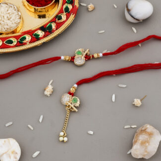 Designer Bhaiya-Bhabhi Rakhi Set with red thread, peacock design, decorative thali with kumkum and chawal, and pearl decorations on beige background.