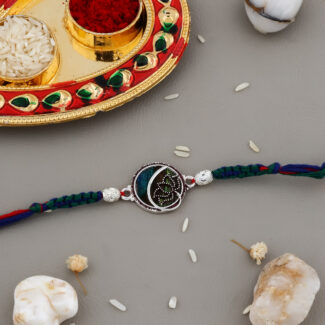 Ethnic-style Bhaiya-Bhabhi Rakhi set with blue-green thread, round golden centerpiece, traditional kumkum-chawal thali, and festive decorative background.